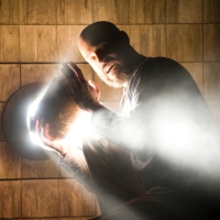 A person holds a rock over a light source. Light streams around them.