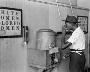 An African American man drinking at a water cooler for “colored” people at a streetcar terminal in Oklahoma City in 1939.