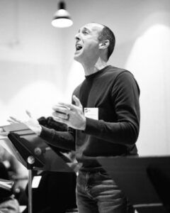 A person sings passionately behind a music stand.