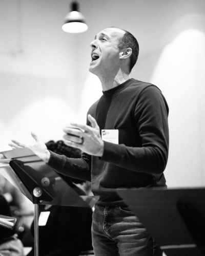 A person sings passionately behind a music stand.