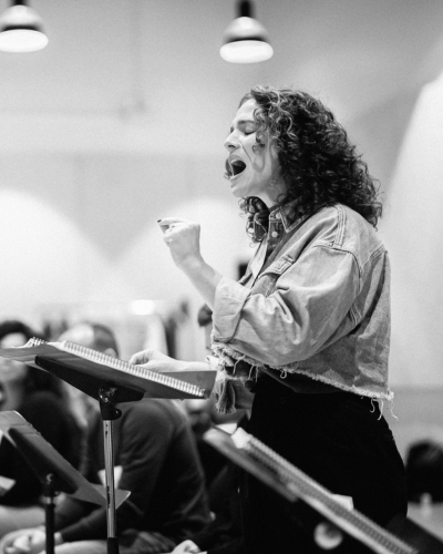 A person sings passionately behind a music stand.