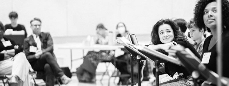 A person leans on a music stand and smiles.