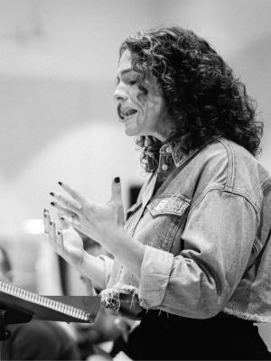 A person stands behind a music stand. They are singing.